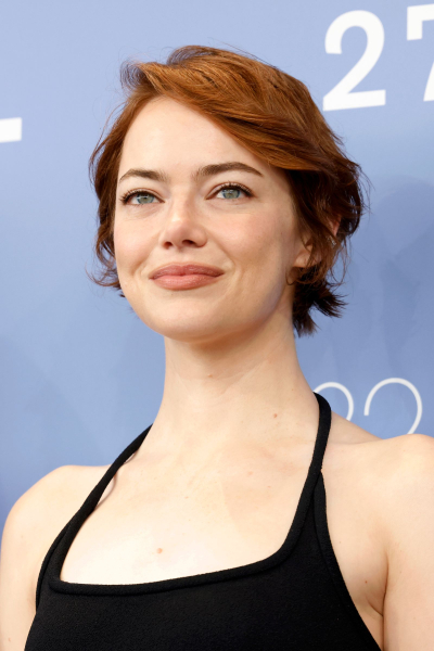 Emma Stone poses at the Venice Film Festival. She wears a black halter top and her hair is in a short cropped bixie cut...